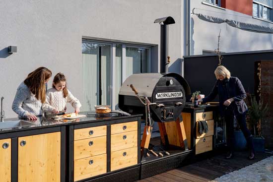 Outdoor-Küche: 6-Schubladen-Modul LOTTI neben Kühlmodul und Ofen, Küchenzeile vor Holzpaneel.