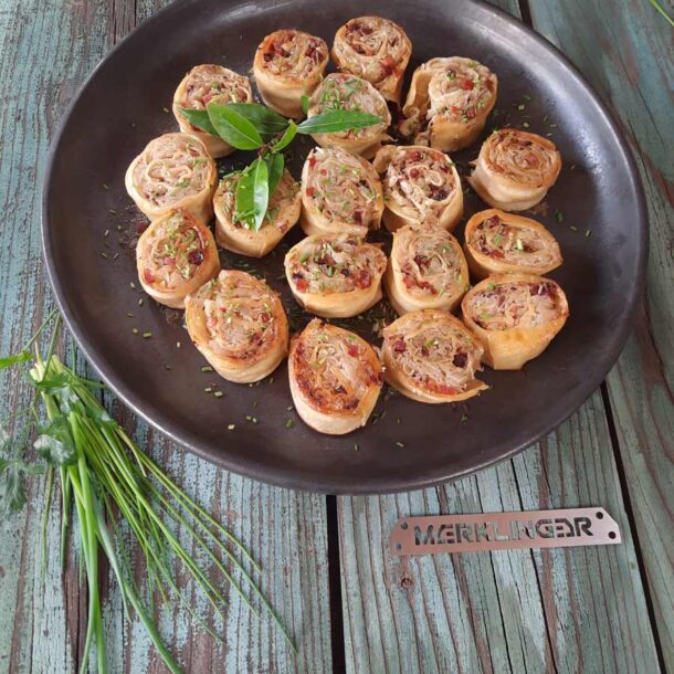 Rustikale Draufsicht: Eine runde dunkle Platte mit herzhaften Teigschnecken, mit Kräutern bestreut; daneben frische Kräuterzweige und ein „MERKLINGER“-Metallschild Rustikale Draufsicht: Eine runde dunkle Platte mit herzhaften Teigschnecken, mit Kräutern bestreut; daneben frische Kräuterzweige und ein „MERKLINGER“-Metallschild Merklinger Zubehör Denkkeramik Keltenschale 05