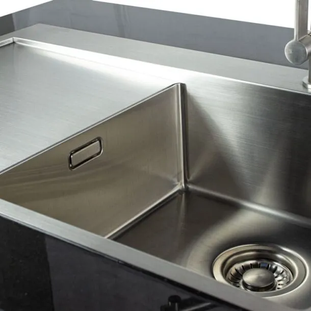 Granit-Arbeitsplatte mit eingelassenem Edelstahl-Spülbecken und Abtropffläche.“