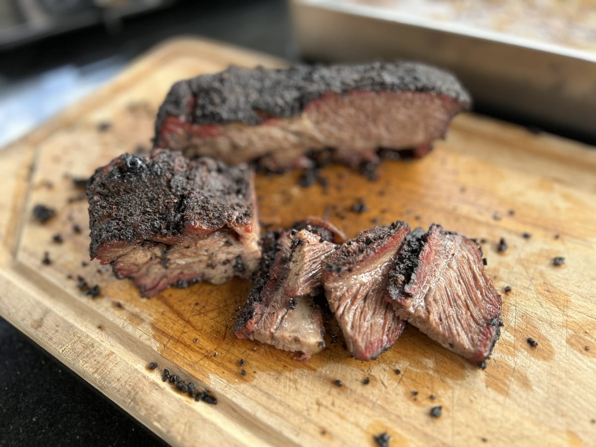 Coffee-Crusted Beef Ribs Saftiges Smoked Beef Brisket mit kräftiger Kruste, aufgeschnitten und serviert auf einem Holzbrett – BBQ-Genuss pur.