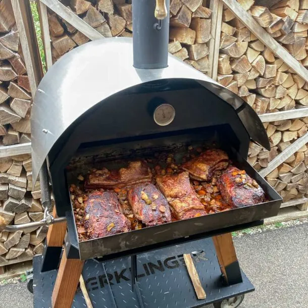 Brat- und Fettwanne im Merklinger Holzbackofen, gefüllt mit Schweinebauch und Gemüse.