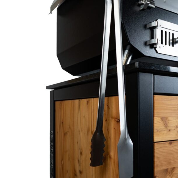 „Zwei MERKLINGER Grillzangen hängen an einem Outdoor-Ofen/Grillwagen mit Holzapplikationen.“ Merklinger Grillzange am Grill