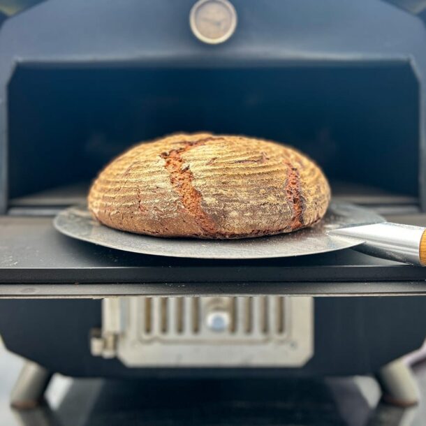 MERKLINGER Brotschieber – Brot sicher entnehmen“ „Rundes Landbrot auf Brotschieber vor dem MERKLINGER Holzbackofen – knusprige Kruste frisch gebacken.“