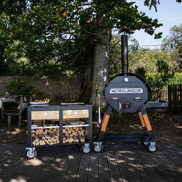 Modul EVA neben MERKLINGER Holzbackofen im Garten; offenes Holzlager und großzügige Arbeitsfläche