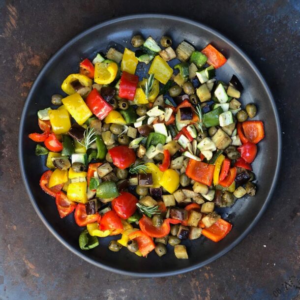 Nahaufnahme einer runden Ofenplatte mit bunt gewürfeltem Ofengemüse – Paprika in Rot/ Gelb/ Grün, Zucchini, Aubergine und Oliven – garniert mit Rosmarin und Knoblauch Merklinger Zubehör Denkkeramik Keltenschale Nahaufnahme einer runden Ofenplatte mit bunt gewürfeltem Ofengemüse – Paprika in Rot/ Gelb/ Grün, Zucchini, Aubergine und Oliven – garniert mit Rosmarin und Knoblauch Merklinger Zubehör Denkkeramik Keltenschale 01