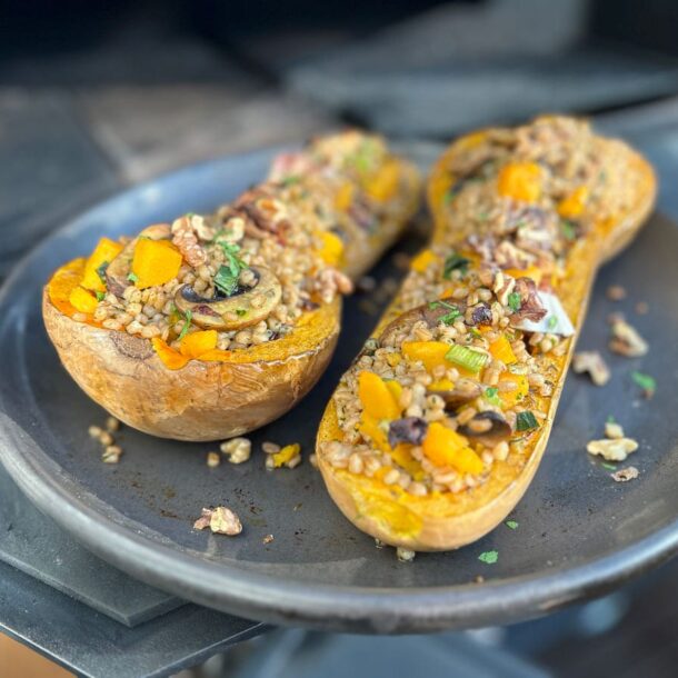 Zwei halbierte und gefüllte Butternut-Kürbisse auf einer dunklen Platte – die Füllung aus Getreidekörnern und Gemüse, teils mit Kräutern bestreut. Zwei halbierte und gefüllte Butternut-Kürbisse auf einer dunklen Platte – die Füllung aus Getreidekörnern und Gemüse, teils mit Kräutern bestreut. DerMerklinger_Holzbackofen_Zubehoer_Denkkeramik_Keltenschale_04-qenup6dy4hsrue7cudwv0isjld7sfvr3tgf9ue6hjo
