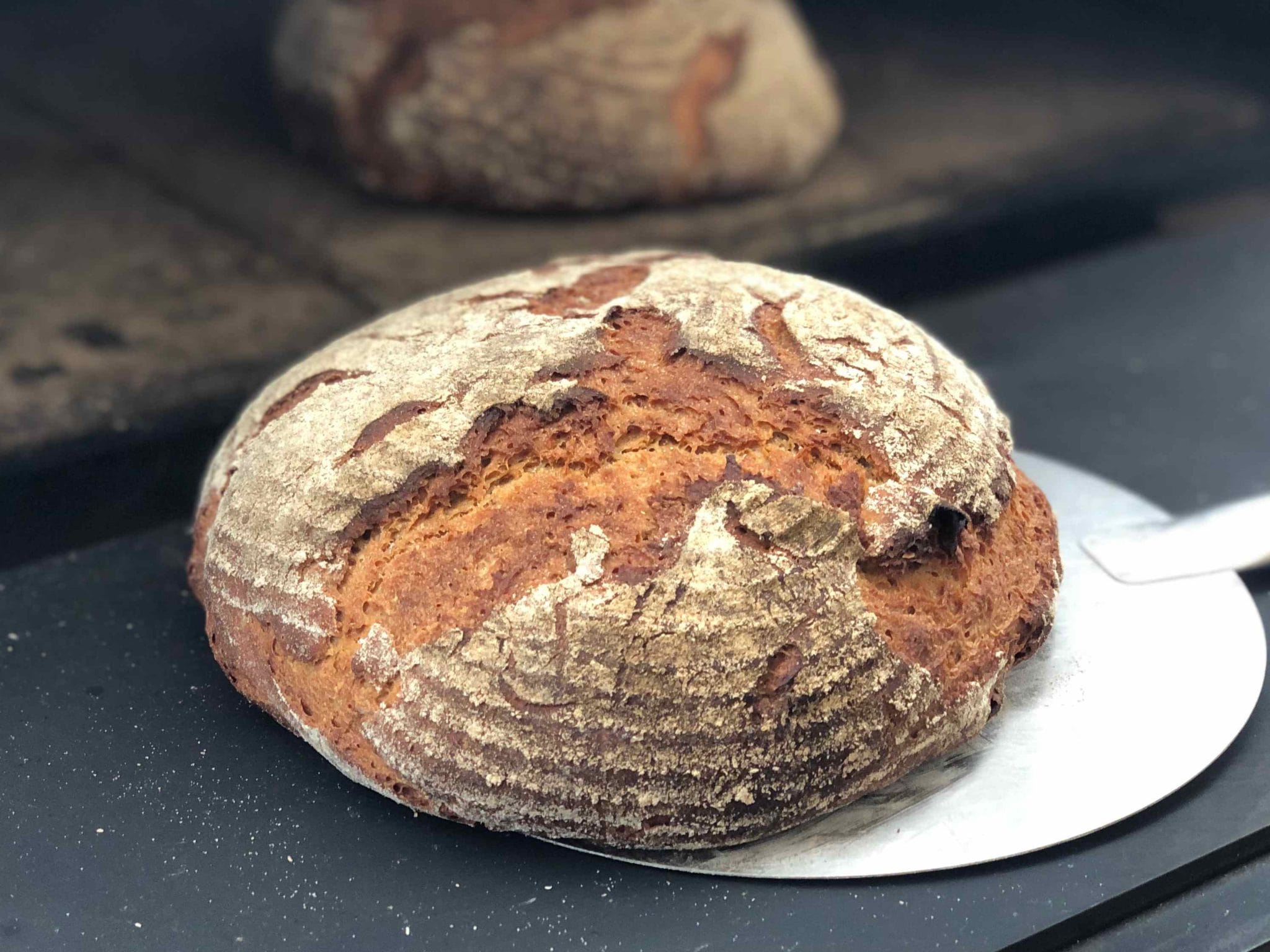 Bierkrusti Rund gebackenes, rustikales Sauerteigbrot mit knuspriger Kruste, frisch aus dem Holzofen geholt.