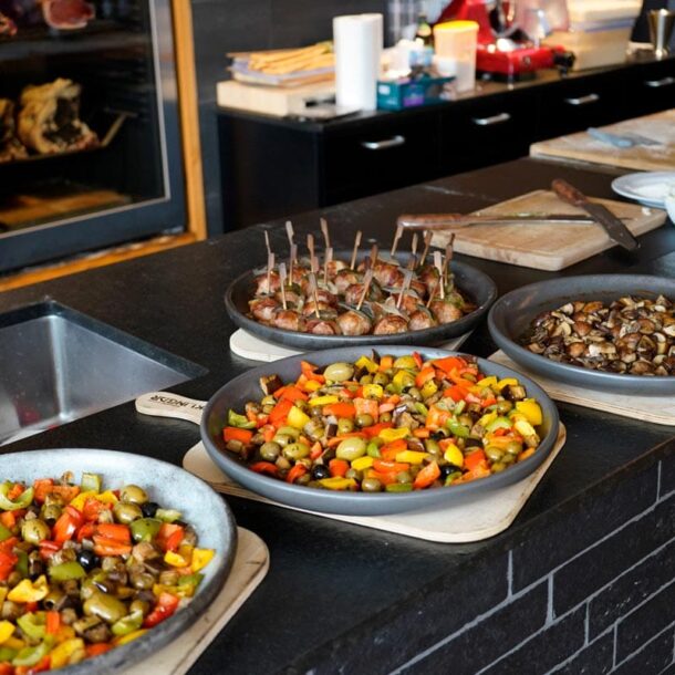 Buffet-/Showküchenszene: Mehrere runde Ofenplatten auf Holzbrettern mit Ofengemüse, Pilzen und Fleischspießen, arrangiert auf einer schwarzen Arbeitsfläche. Merklinger Zubehör Denkkeramik Keltenschale 2 (4 Stück) mit Essen Buffet-/Showküchenszene: Mehrere runde Ofenplatten auf Holzbrettern mit Ofengemüse, Pilzen und Fleischspießen, arrangiert auf einer schwarzen Arbeitsfläche. Merklinger Zubehör Denkkeramik Keltenschale 2 (4 Stück) mit Essen