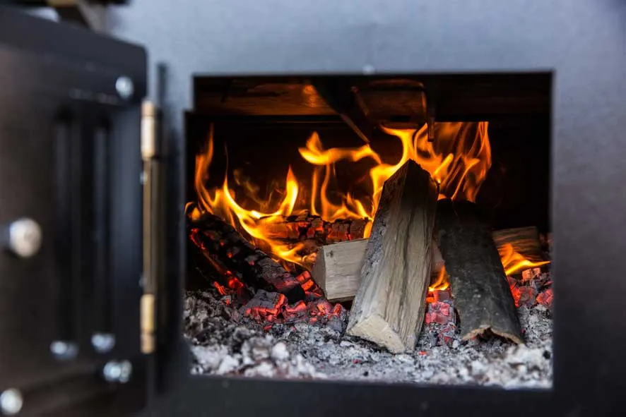 Blick in Brennraum des MERKLINGER Ofens mit glühenden Holzscheiten und Asche.