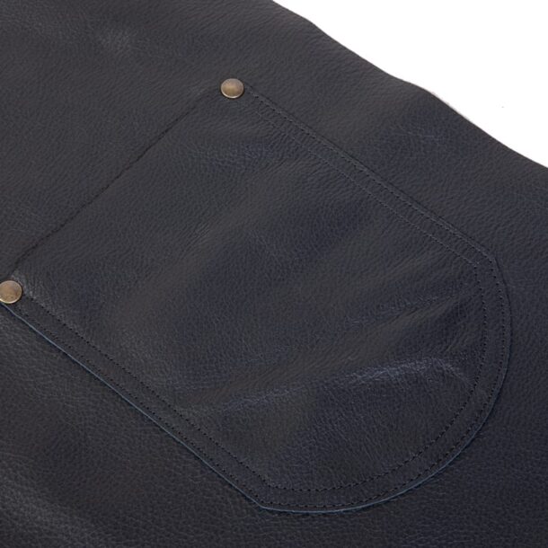 „Lederschürze – Fronttasche Detail | MERKLINGER“ Dateiname: merklinger-lederschuerze-fronttasche-detail.jpg Fronttasche der MERKLINGER Lederschürze – vernietet und doppelt abgesteppt, Narbenlederstruktur.“