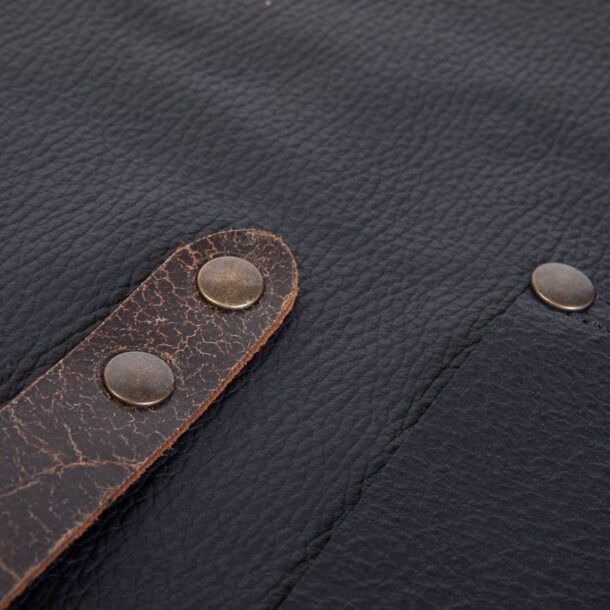 „Lederschürze – Riemen & Nieten Detail | MERKLINGER“ Dateiname: merklinger-lederschuerze-riemen-nieten-detail.jpg „Riemen und Messingnieten der MERKLINGER Lederschürze in Nahaufnahme – robuste Verarbeitung.“
